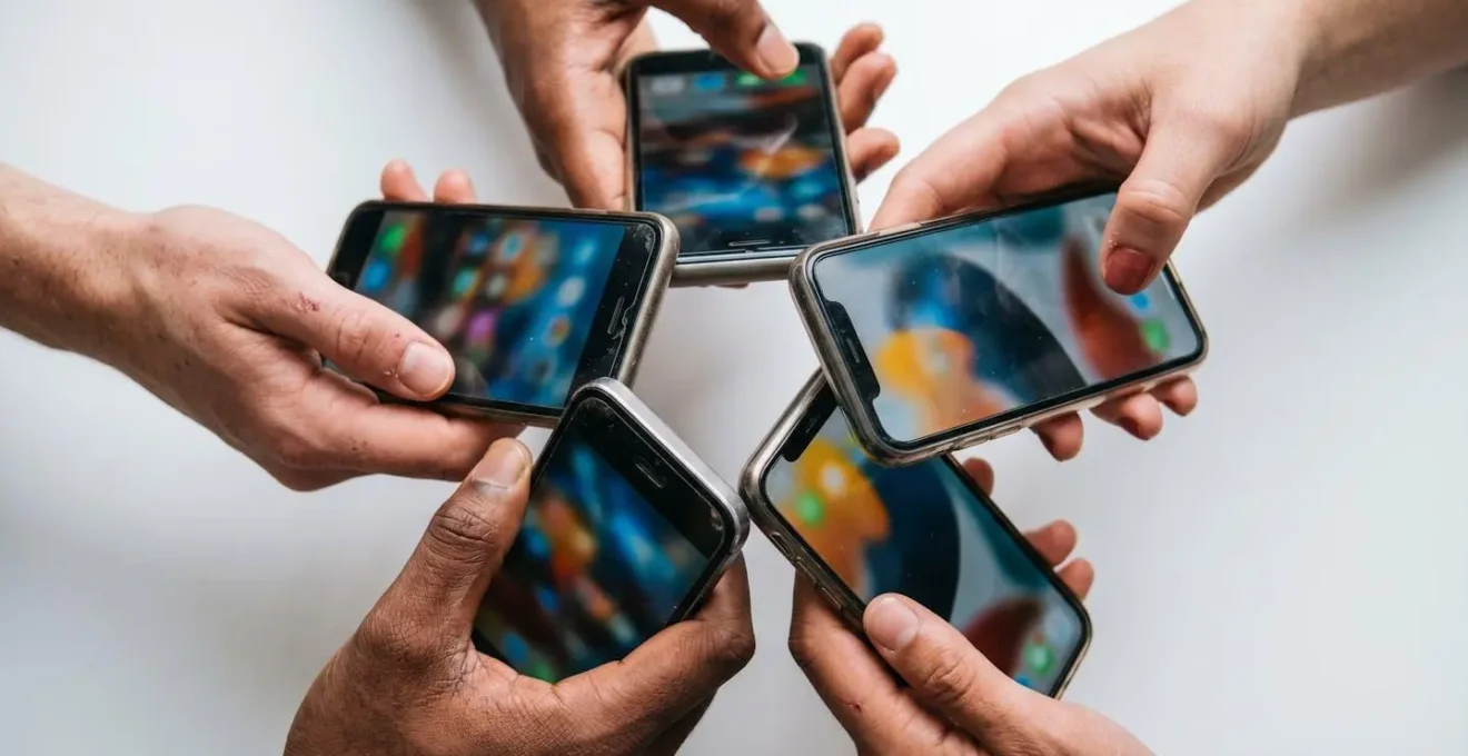Vue macro de mains tenant des smartphones en cercle, montrant différentes créations visuelles colorées